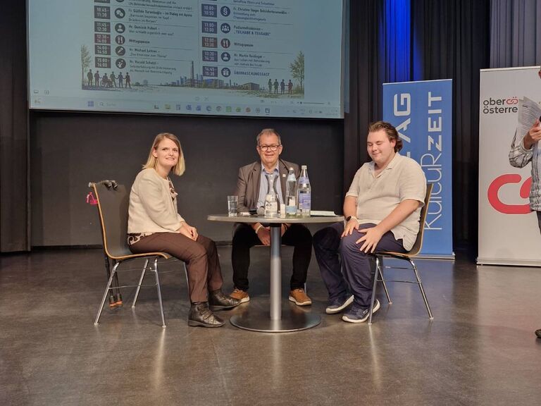 drei MEnschen sitzen auf Bühne