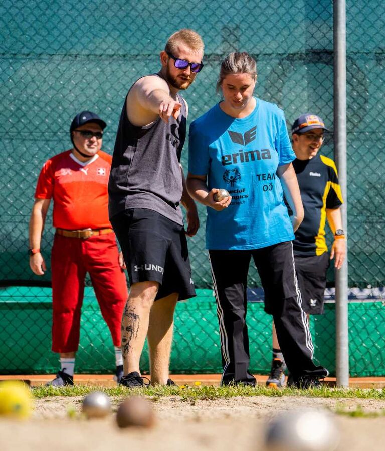 Mehrere junge Menschen spielen im Aussenbereich gemeinsam Boccia