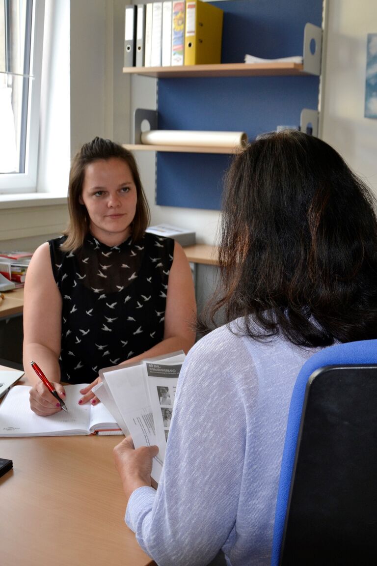 Zwei Frauen sitzen sich in einem Büro gegenüber und führen ein Beratungsgespräch mit Unterlagen auf dem Tisch – persönliche Beratung in ruhiger Atmosphäre.