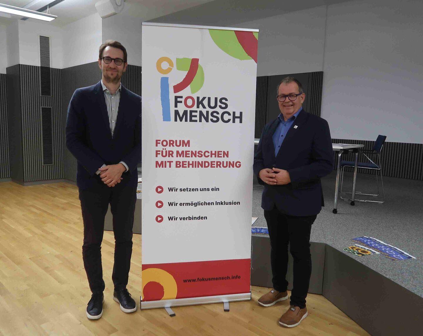 zwei Männer stehen vorm Roll Up von Fokus Mensch