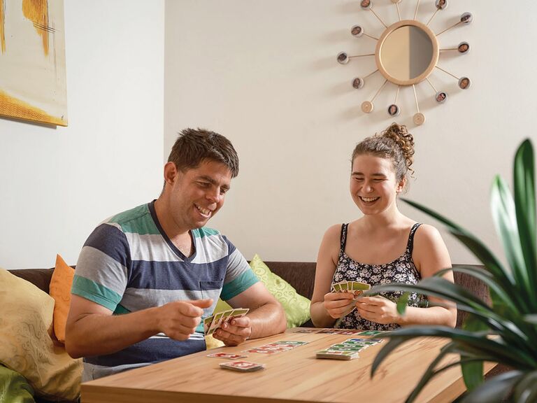 Zwei junge Erwachsene sitzen an einem Tisch und spielen gemeinsam Karten – unterstütztes Wohnen mit gemeinsamer Alltagsgestaltung.