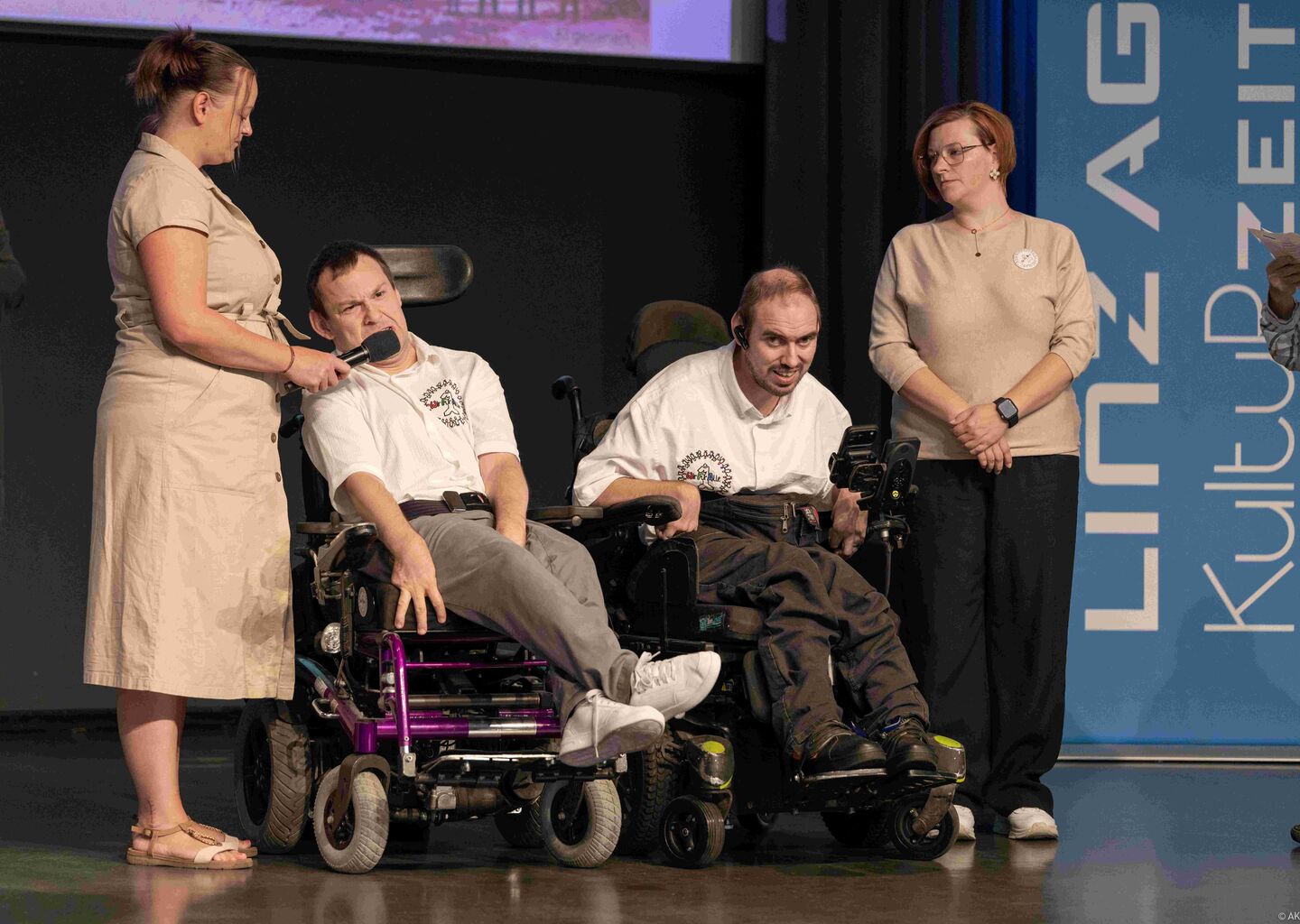 Podiumsgespräch, zwei Personen im Rollstuhl flankiert von Persönlicher Assistenz