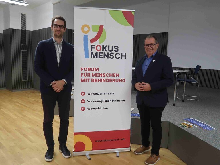 zwei Männer stehen vorm Roll Up von Fokus Mensch
