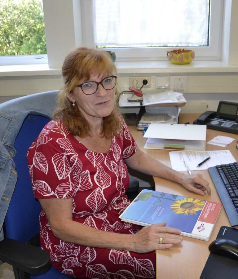 Eine Frau sitzt an einem Schreibtisch in einem Büro und arbeitet am Computer.