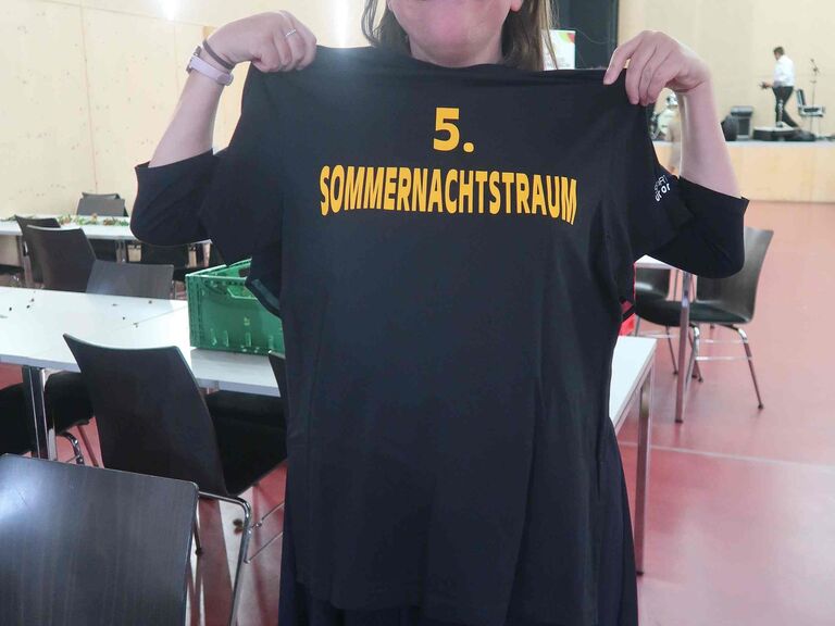 Frau hält TShirt hoch, auf dem steht: 5. Sommernachtstraum