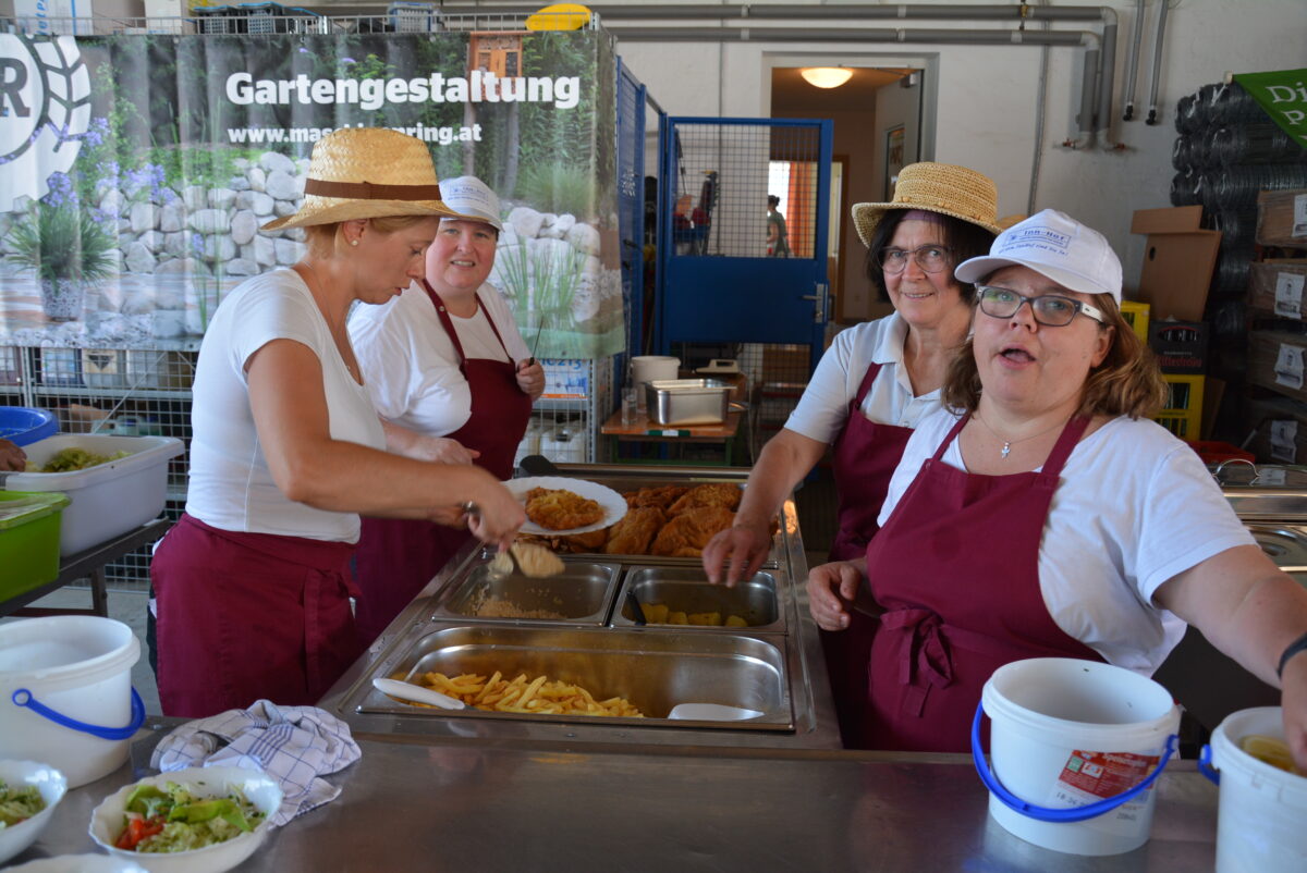 vier Frauen bei der Essensausgabe: Schnitzel und Pommes Frites
