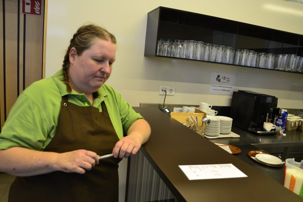 eine Frau steht an der Theke und schaut auf einen Zettel