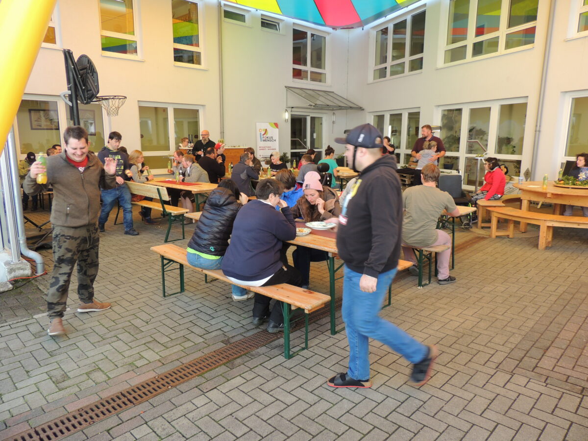 Innenhof, Gruppe von Menschen auf Bierbänken, plaudern und essen 