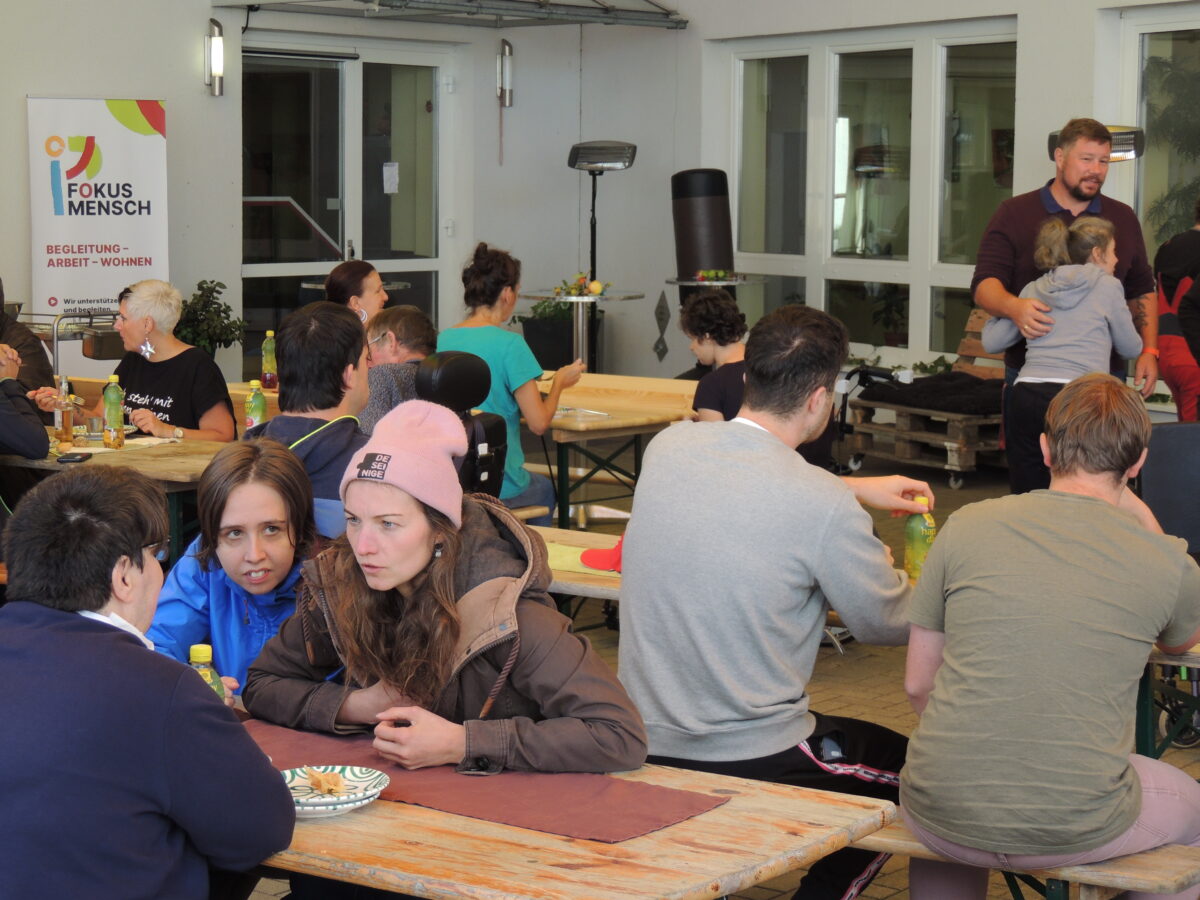 Menschen im Innenhof, sitzen auf Bierbänken