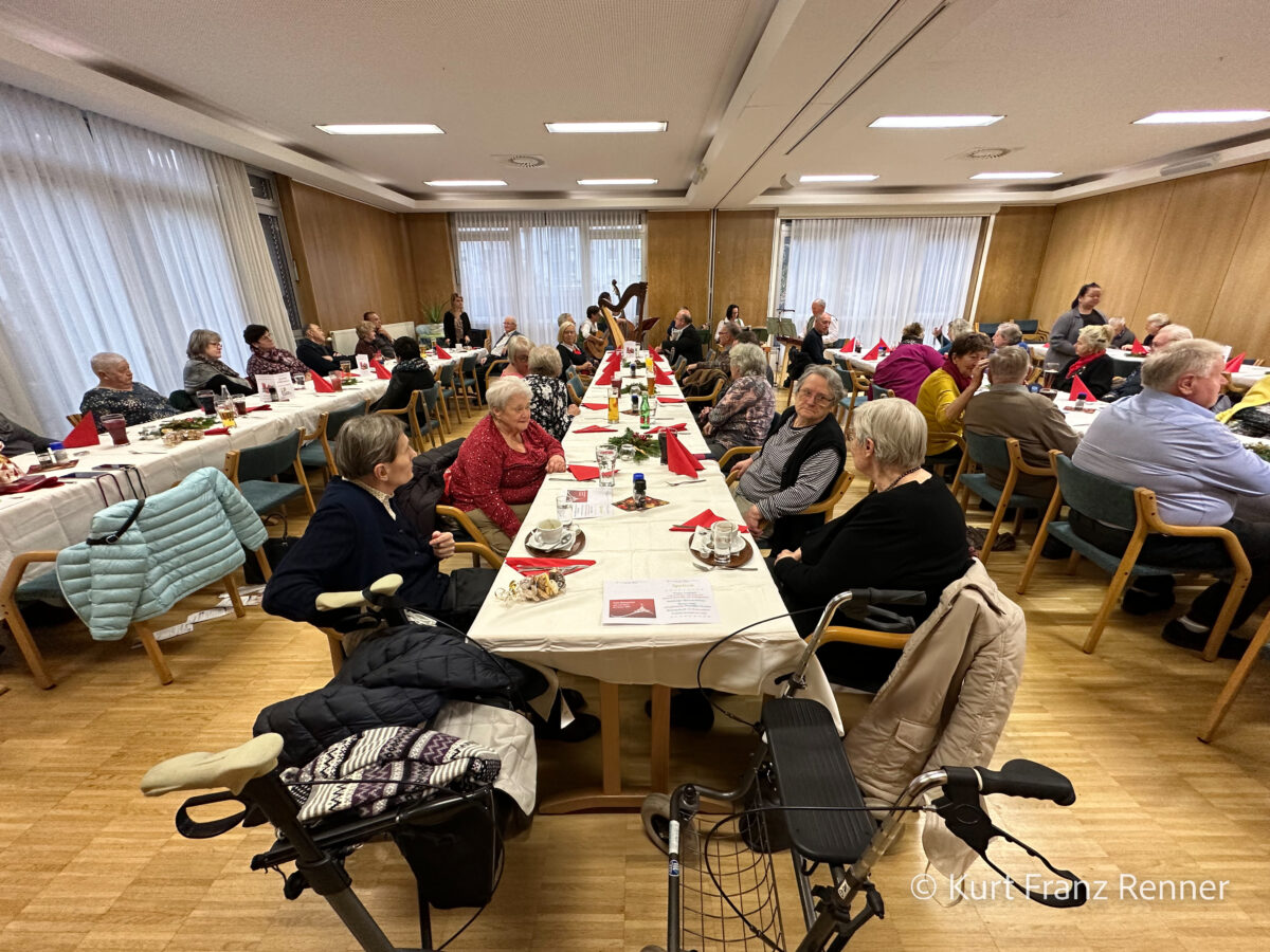 viele Gäste sitzen an langen Esstischen