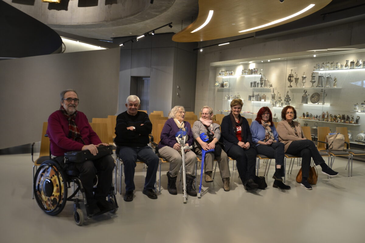 Gruppe von Menschen sitzt in der Sesselreihe und schaut in die Kamera