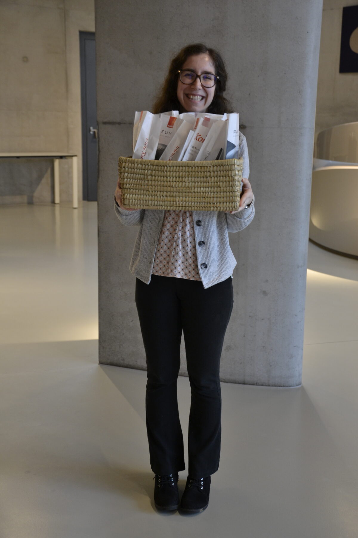 Frau lächelt strahlend, hält Kornspitz-Gebäck Korb in die Kamera