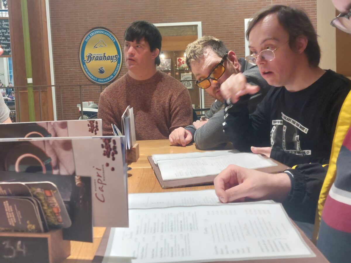 zu Gast in der Pizzeria, Menschen sitzen bei Tische und schauen in die Speisekarte