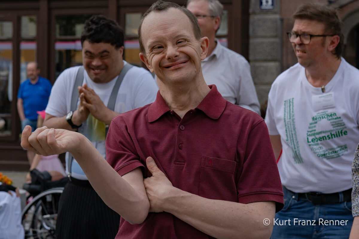 breit lachender Mann in weinrotem Polo-Shirt