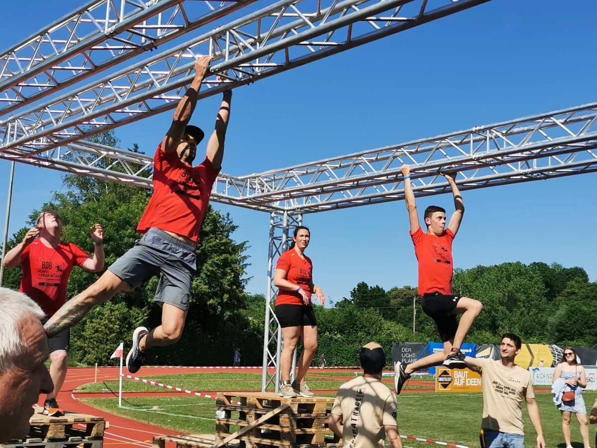junge Menschen hanteln sich am Gerüst entlang
