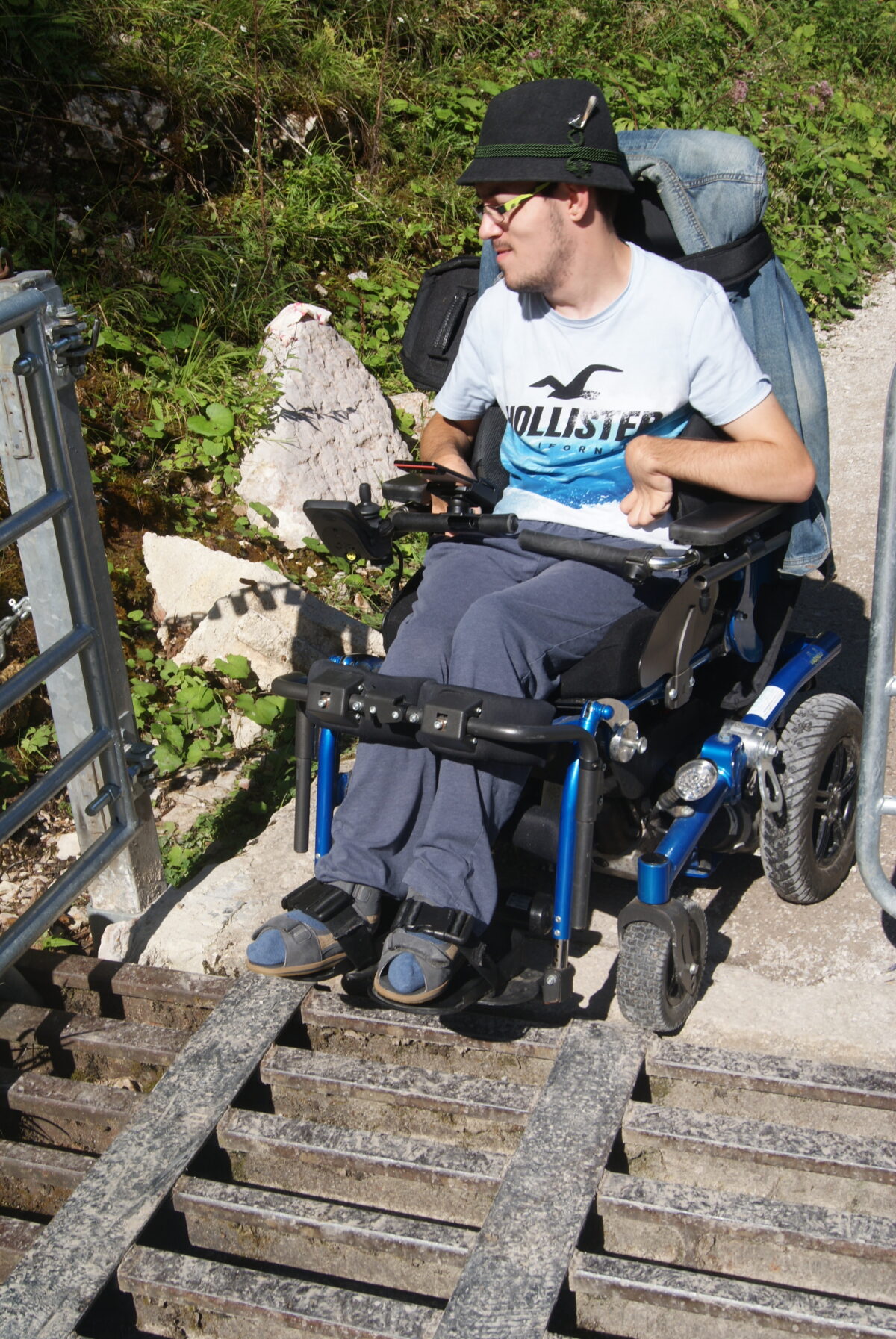 Mann im Rollstuhl fährt über Kuhgatter