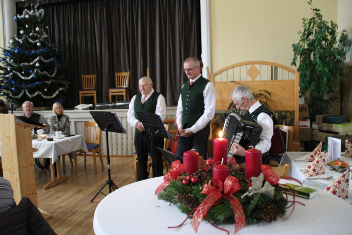 im Vordergrund ein Adventkrant, Musiktrio