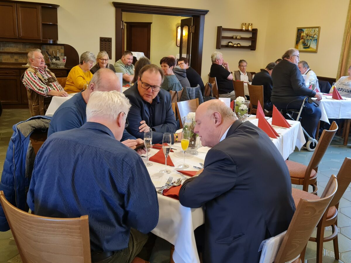 Plauderei mehrerer Personen bei Tisch