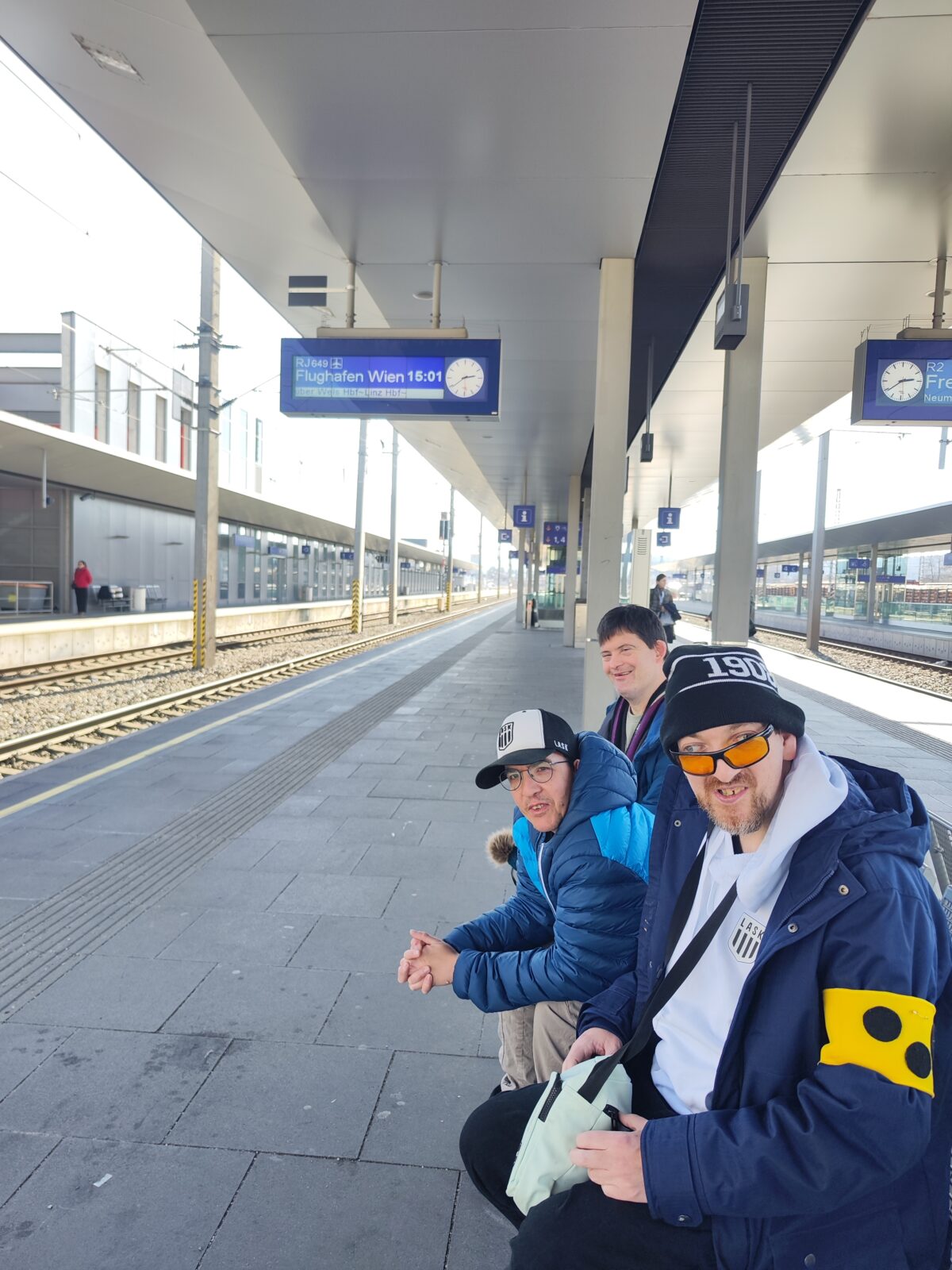 Menschen sitzen auf dem Bahnsteig und warten auf den Zug