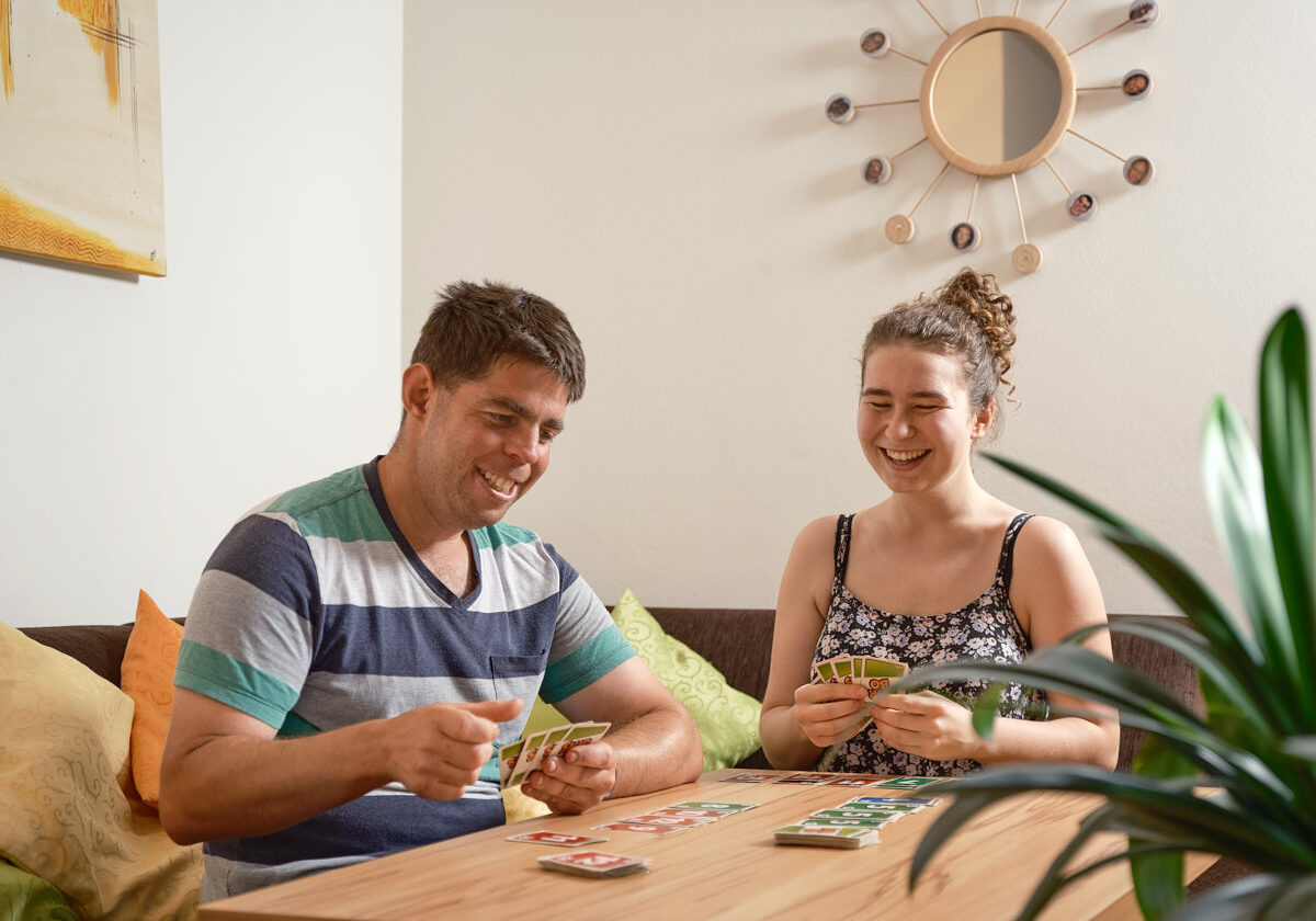 zwei junge Menschen spielen miteinander Karten und lachen