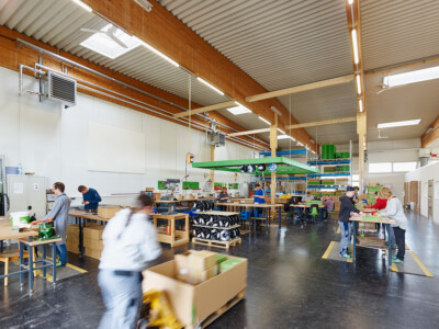 Menschen arbeiten in einer Werkstatt in einer Lagerhalle in Taufkirchen an der Pram