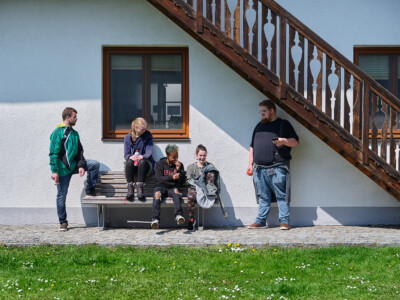 fünf junge Menschen machen Pause bei einer Bank im Innenhof vom Hof Tollet